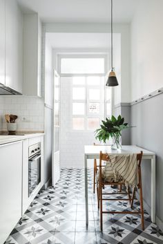 a white kitchen with black and white checkered flooring, potted plant on the table