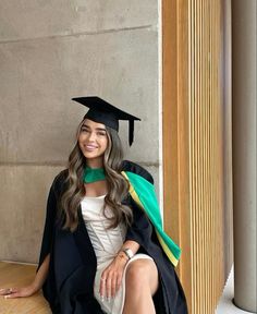 a woman sitting on the ground wearing a graduation cap and gown