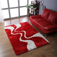 a living room with a red couch and white area rugs on the wooden floor