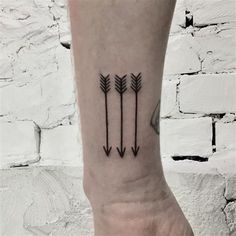 an arrow tattoo on the wrist is shown in black ink, with three arrows pointing upward