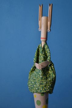 a wooden doll with green and yellow polka dots on it's body, holding two forks