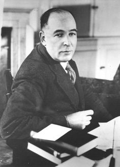 an old photo of a man sitting at a desk with papers and pens in front of him