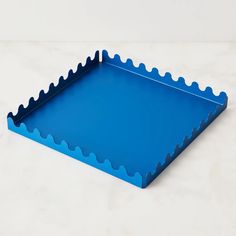 a blue tray with scalloped edges on a white surface