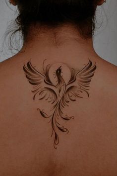 the back of a woman's neck with a bird tattoo on her left side