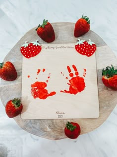 strawberry handprints and strawberries on a wooden board