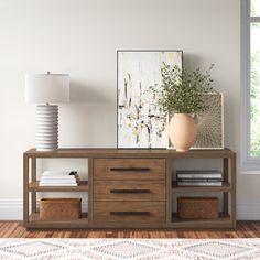 a living room with a large window and a wooden cabinet on the floor next to a lamp