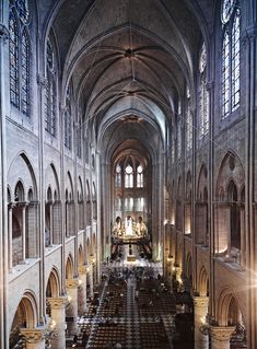 the inside of a large cathedral with pews and stained glass windows on both sides