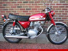 a red motorcycle parked next to a brick wall