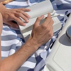 a man laying on top of a blue and white blanket next to an electronic device