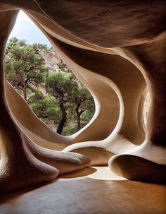 the inside of a building with trees and rocks on it's sides, as seen through an opening in the wall