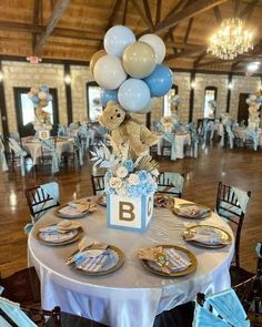 a teddy bear centerpiece on top of a table with blue and white decorations in the middle