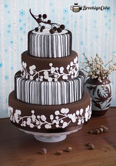 a three tiered cake sitting on top of a table next to a vase with flowers