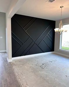 an empty room with black walls and wood flooring in the middle of it is being remodeled