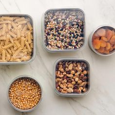 four containers filled with different types of food on top of a white countertop next to each other