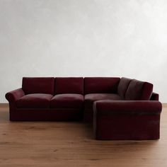 a red couch sitting on top of a wooden floor next to a chair and ottoman