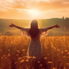 a woman standing in a field with her arms spread out to the sun behind her