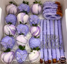 a box filled with purple and white chocolate covered strawberries next to other candy items