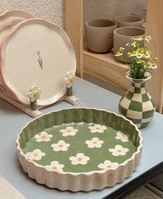 a table topped with plates and vases filled with flowers next to each other on top of a blue counter