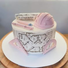 a cake made to look like a house with construction plans on top and pink trimmings