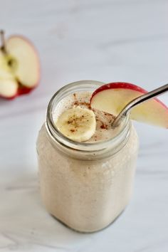 an apple and banana smoothie in a mason jar with a spoon on the side