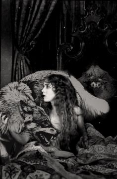 a woman laying in bed next to a wolf