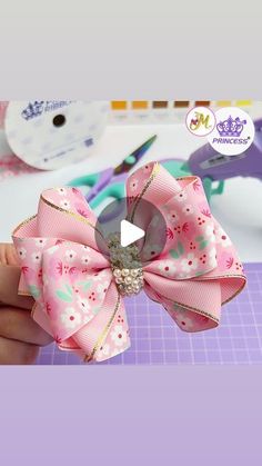 a person is holding a pink bow with flowers on it and scissors in the background