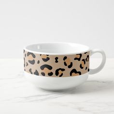 a leopard print coffee cup on a marble countertop with a white bowl in the foreground