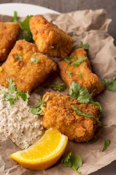 fried food on a plate with lemon wedges and garnish