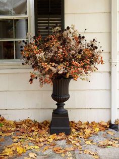 a vase filled with lots of flowers sitting in front of a house