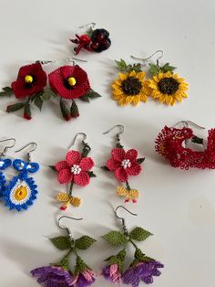 crocheted flower earrings are arranged on a white surface with flowers in the middle