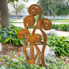 a metal sculpture in the shape of two people holding hands and standing next to some plants