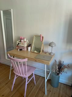 a wooden desk topped with a pink chair next to a mirror