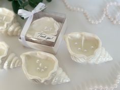 three seashells are sitting on a table with pearls and a thank you tag