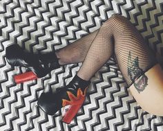 a woman laying on top of a bed wearing fishnet stockings and high heeled boots