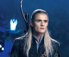 a man with long blonde hair and blue eyes is holding an arrow in his hand