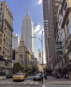 a city street with tall buildings in the background and cars parked on the side of the road