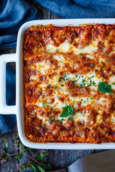 a casserole dish with meat, cheese and herbs in it on a wooden table