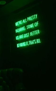 a green neon sign that says we're all pretty bizarre some of us are just better at hiding, that's all