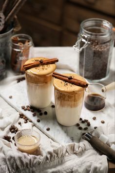 two cups filled with coffee and cinnamon on top of a table