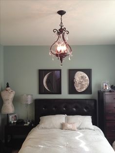 a bedroom with two pictures on the wall and a chandelier hanging from the ceiling