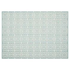 an area rug with white and blue geometric designs on the front, along with a light green border