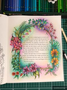 an open book with flowers on it next to crayon markers and colored pencils