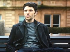 a man sitting on top of a wooden bench