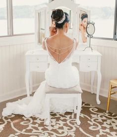 a woman sitting in front of a white vanity