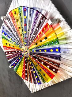 a multicolored paper fan sitting on top of a cement floor next to a wall