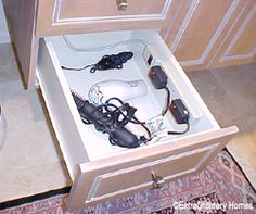 an open drawer with hair dryer and other items in it next to a sink