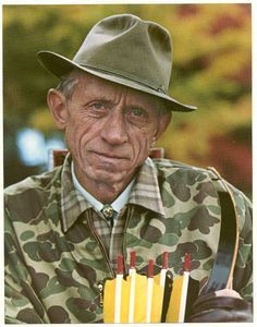 an older man wearing a hat and holding matches in one hand while looking at the camera