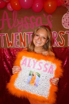 a woman holding up an orange sign with the name alyssa written on it