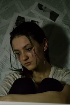 a woman sitting in front of a laptop computer on top of a table next to a pile of papers