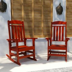 two red rocking chairs sitting next to each other in front of a window with shutters